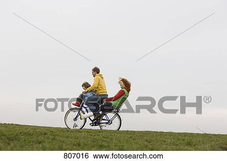 Stock Photograph - A young family riding on a bike together. Fotosearch