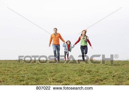 Stock Image - A young family running together in a park. Fotosearch