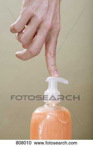 Stock Image - A human finger pushing a hand soap dispenser. Fotosearch