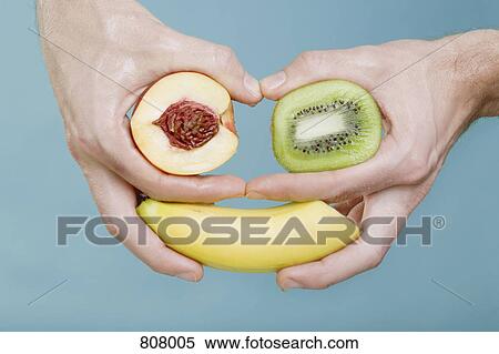 Stock Photography - Human hands holding fruit in an arrangement that looks like a face. Fotosearch