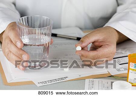 Stock Photography - A doctor offering a pill and glass of water. Fotosearch