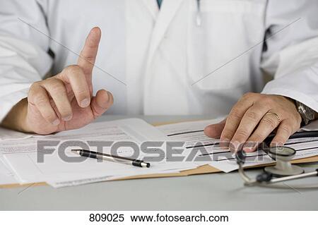 A doctor sitting at a desk View Large Photo Image Stock Photography - A doctor sitting at a desk. Fotosearch