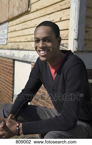 A young man sitting on porch steps View Large Photo Image Stock Image - A young man sitting on porch steps. Fotosearch