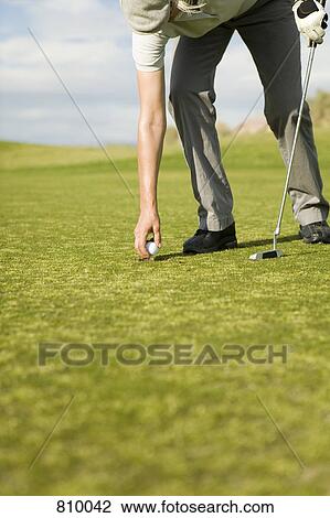Stock Image - A woman putting a golf ball on a tee. Fotosearch