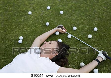 Picture - An exhausted golfer lying down on a golf course. Fotosearch