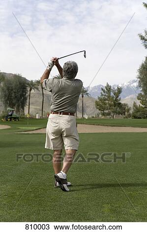 Stock Image - Rear view of a man playing golf, Palm Springs, California, USA. Fotosearch