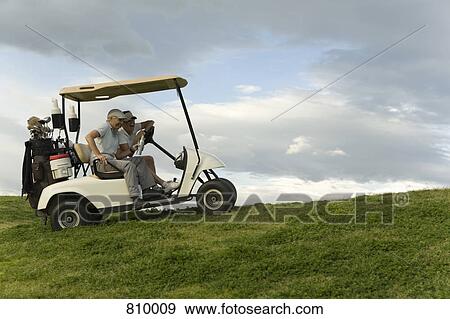 Two golfers sitting in a golf cart and laughing View Large Photo Image Stock Photo - Two golfers sitting in a golf cart and laughing. Fotosearch