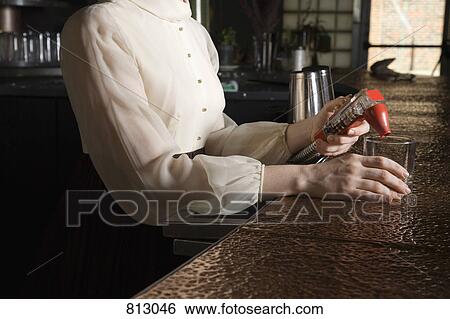 A bartender pouring a drink at a bar View Large Photo Image Stock Photograph - A bartender pouring a drink at a bar. Fotosearch