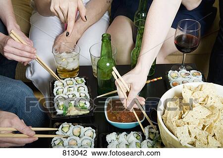 Stock Image - A group of friends eating and drinking together. Fotosearch