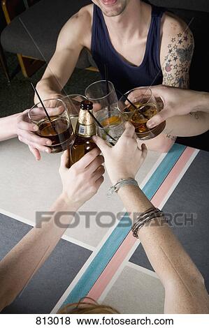 A group of friends toasting drinks at a bar View Large Photo Image Stock Photo - A group of friends toasting drinks at a bar. Fotosearch