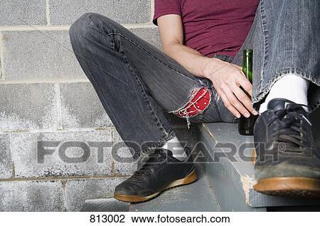 A man sitting on a step and holding a bottle of beer View Large Photo Image Stock Image - A man sitting on a step and holding a bottle of beer. Fotosearch