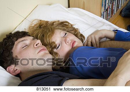 Stock Image - A young couple lying in bed together. Fotosearch