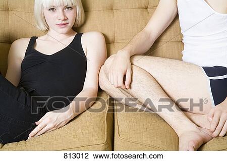 Stock Image - A young couple sitting on a sofa together. Fotosearch