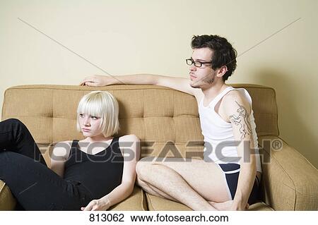 A young couple sitting on a sofa View Large Photo Image Stock Image - A young couple sitting on a sofa. Fotosearch