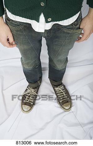 Stock Photograph - A young man dressed in jeans and canvas sneakers. Fotosearch
