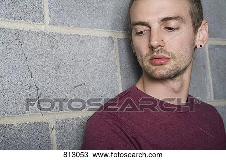 A young man leaning against a brick wall and looking away View Large Photo Image Stock Image - A young man leaning against a brick wall and looking away. Fotosearch