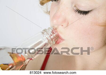 Picture - A young woman drinking from a glass bottle. Fotosearch