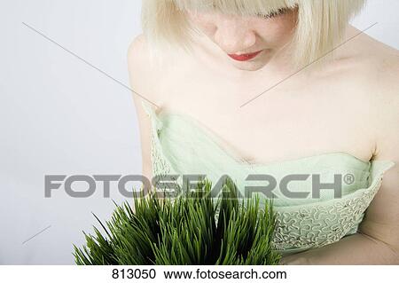 Stock Image - A young woman holding a wheatgrass plant. Fotosearch