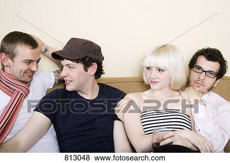 Stock Photo - Four friends sitting on a sofa. Fotosearch