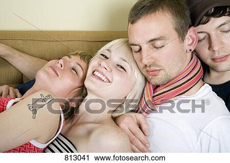 Four friends sitting together on a sofa View Large Photo Image Stock Image - Four friends sitting together on a sofa. Fotosearch