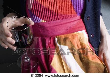 Midsection of a young woman holding a glass of red wine View Large Photo Image Picture - Midsection of a young woman holding a glass of red wine. Fotosearch
