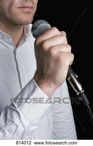 A man holding a microphone View Large Photo Image Stock Image - A man holding a microphone. Fotosearch