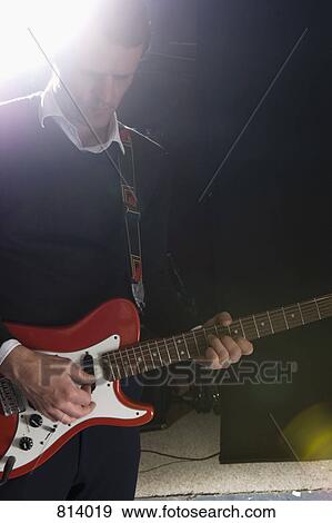 Stock Photo - A man playing an electric guitar on stage. Fotosearch