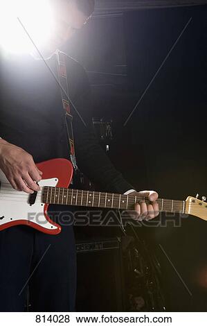 A man playing an electric guitar on stage View Large Photo Image Stock Photo - A man playing an electric guitar on stage. Fotosearch