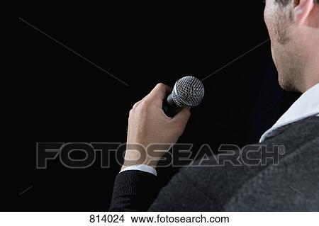 Rear view of a man holding a microphone View Large Photo Image Picture - Rear view of a man holding a microphone. Fotosearch