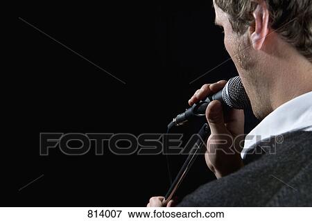 Rear view of a man singing into a microphone View Large Photo Image Stock Photo - Rear view of a man singing into a microphone. Fotosearch