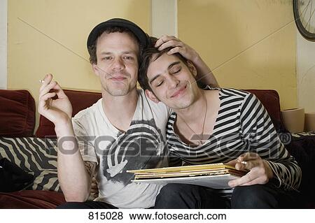 A young couple sitting together on a sofa View Large Photo Image Stock Photo - A young couple sitting together on a sofa. Fotosearch