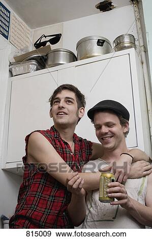 A young couple standing together in a kitchen View Large Photo Image Stock Photo - A young couple standing together in a kitchen. Fotosearch