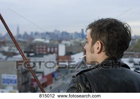 Stock Image - A young man smoking a cigarette on a fire escape. Fotosearch
