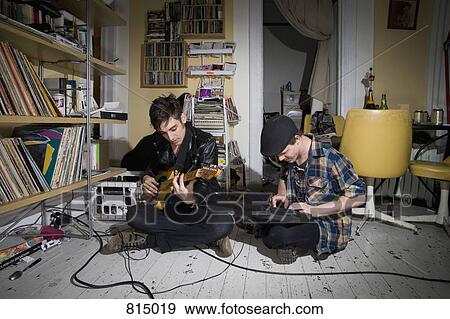 Two young men playing instruments in their living room View Large Photo Image Stock Photo - Two young men playing instruments in their living room. Fotosearch