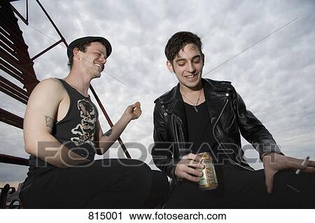 Two young men sitting on a fire escape smoking and drinking View Large Photo Image Stock Image - Two young men sitting on a fire escape smoking and drinking. Fotosearch