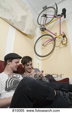Stock Photography - Two young men sitting on a sofa together. Fotosearch