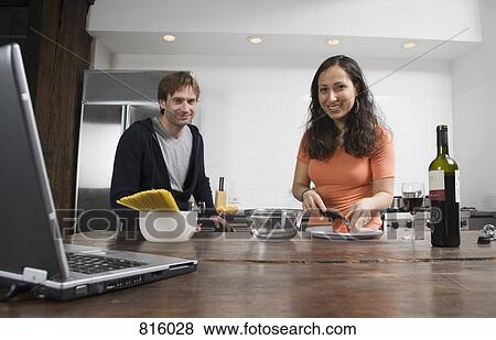 Stock Photo - A couple preparing dinner in the kitchen. Fotosearch