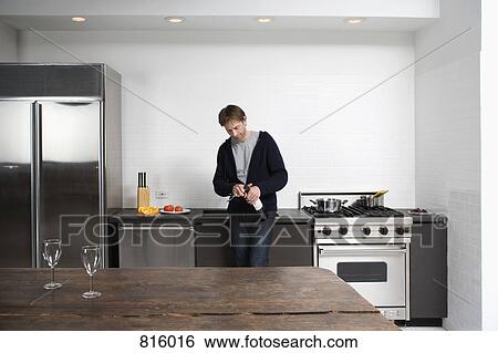 Stock Photograph - Man opening bottle of wine in the kitchen. Fotosearch