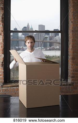 Man unpacking cardboard box in office View Large Photo Image Stock Photo - Man unpacking cardboard box in office. Fotosearch