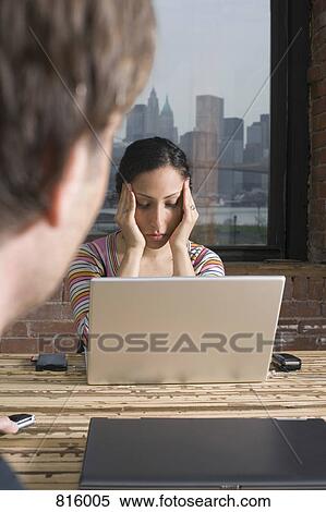 Stock Photography - Woman sitting at laptop looking stressed. Fotosearch