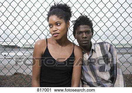 A young couple in front of a chainlink fence View Large Photo Image Stock Image - A young couple in front of a chainlink fence. Fotosearch