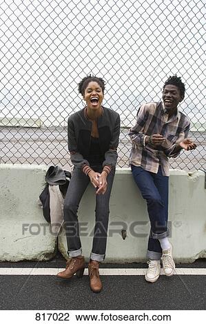 A young couple standing in front of a chainlink fence View Large Photo Image Stock Image - A young couple standing in front of a chainlink fence. Fotosearch