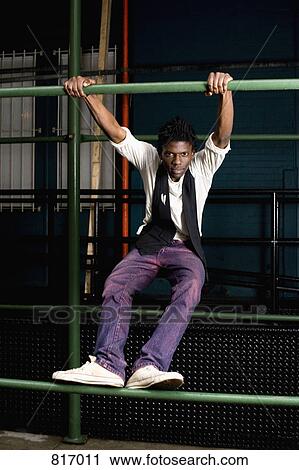 A young man holding onto a metal bar View Large Photo Image Stock Image - A young man holding onto a metal bar. Fotosearch