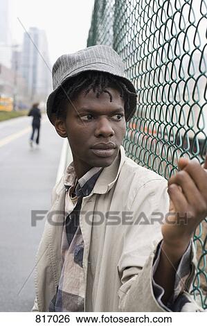 A young man leaning against a chainlink fence View Large Photo Image Stock Photograph - A young man leaning against a chainlink fence. Fotosearch