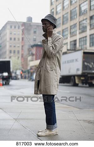 A young man standing on a sidewalk and using a mobile phone View Large Photo Image Stock Image - A young man standing on a sidewalk and using a mobile phone. Fotosearch