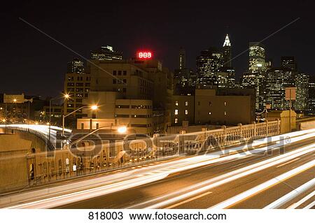 Stock Image - Expressway on the Brooklyn Bridge and Manhattan skyline at night, New York City. Fotosearch