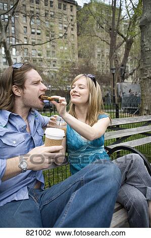 A woman feeding a man a cookie in a park, Central Park, New York City View Large Photo Image Stock Image - A woman feeding a man a cookie in a park, Central Park, New York City. Fotosearch