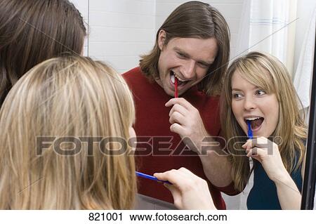 Stock Image - A young couple brushing their teeth together. Fotosearch