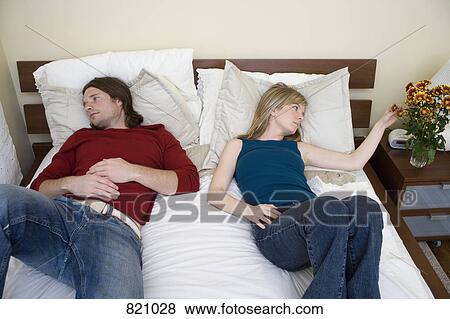 A young couple lying down on a bed View Large Photo Image Stock Photo - A young couple lying down on a bed. Fotosearch