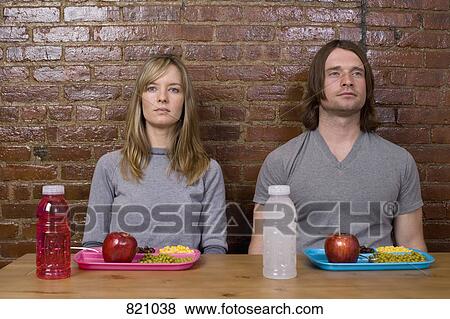 A young couple sitting at a table with sports drinks and plastic trays of food View Large Photo Image Stock Photo - A young couple sitting at a table with sports drinks and plastic trays of food . Fotosearch